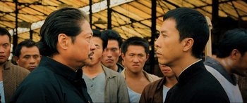 Movie still from “Ip Man 2” (2010), directed by Wilson Yip – A group of men standing next to each other; Close Up shot, Over the shoulder angle