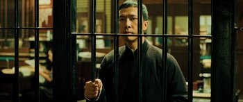 Movie still from “Ip Man 2” (2010), directed by Wilson Yip – A man standing behind bars in a jail cell; Medium shot, Low angle
