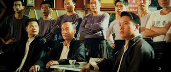 Movie still from “Ip Man 2” (2010), directed by Wilson Yip – A group of men standing around a table with cups; Medium shot, Low angle