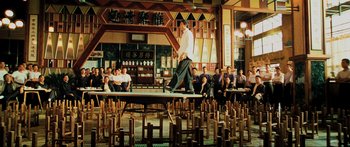 Movie still from “Ip Man 2” (2010), directed by Wilson Yip – A group of people sitting and standing in a room; Wide shot, High angle