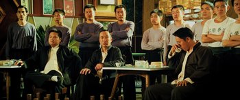 Movie still from “Ip Man 2” (2010), directed by Wilson Yip – A group of men standing around a table with their arms crossed; Medium shot, Low angle