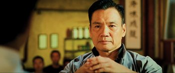 Movie still from “Ip Man 2” (2010), directed by Wilson Yip – An older asian man is looking at the camera; Close Up shot, Low angle