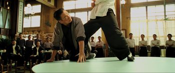 Movie still from “Ip Man 2” (2010), directed by Wilson Yip – Two men are wrestling on the floor in front of a crowd of onlookers; Medium shot, Over the shoulder angle