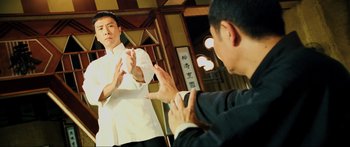 Movie still from “Ip Man 2” (2010), directed by Wilson Yip – Two men in suits are practicing martial arts; Medium shot, Over the shoulder angle