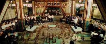 Movie still from “Ip Man 2” (2010), directed by Wilson Yip – A group of people sitting around a table with chairs around it; Extreme Wide shot, High angle