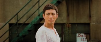 Movie still from “Ip Man 2” (2010), directed by Wilson Yip – A man in a white t - shirt is looking at the camera; Close Up shot, Low angle