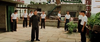 Movie still from “Ip Man 2” (2010), directed by Wilson Yip – A group of men standing on top of a brick walkway; Wide shot, Low angle