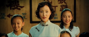 Movie still from “Ip Man 2” (2010), directed by Wilson Yip – A woman in a cheongsam is posing for a picture; Close Up shot, Low angle