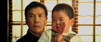 Movie still from “Ip Man 2” (2010), directed by Wilson Yip – A man and a child holding a lollipop; Close Up shot, Over the shoulder angle