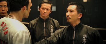 Movie still from “Ip Man 2” (2010), directed by Wilson Yip – Two men in black jackets are standing next to each other; Medium shot, Over the shoulder angle