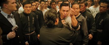 Movie still from “Ip Man 2” (2010), directed by Wilson Yip – A group of people standing in a room; Medium shot, Over the shoulder angle