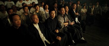 Movie still from “Ip Man 2” (2010), directed by Wilson Yip – A group of people sitting in a room watching a show; Wide shot, High angle
