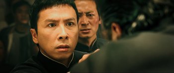 Movie still from “Ip Man 2” (2010), directed by Wilson Yip – A man looking at himself in the mirror in front of another man; Close Up shot, Over the shoulder angle