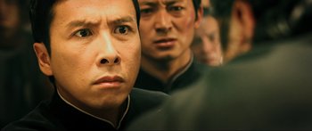 Movie still from “Ip Man 2” (2010), directed by Wilson Yip – A man in a black shirt is looking at the camera; Close Up shot, Over the shoulder angle