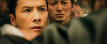 Movie still from “Ip Man 2” (2010), directed by Wilson Yip – Two asian men looking into the camera with one of them looking at the camera; Close Up shot, Over the shoulder angle