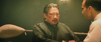 Movie still from “Ip Man 2” (2010), directed by Wilson Yip – A man in a black shirt is sitting down; Close Up shot, Over the shoulder angle