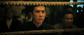 Movie still from “Ip Man 2” (2010), directed by Wilson Yip – A man in black shirt looking at the camera; Close Up shot, Low angle