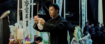 Movie still from “Ip Man 2” (2010), directed by Wilson Yip – A man in black shirt holding a stick; Medium shot, Low angle