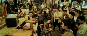 Movie still from “Ip Man 2” (2010), directed by Wilson Yip – A large group of people sitting around a table in a room; Wide shot, High angle