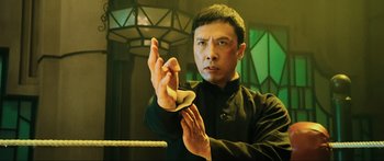 Movie still from “Ip Man 2” (2010), directed by Wilson Yip – A man in a black shirt is holding something in his hands; Medium shot, Low angle