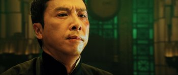 Movie still from “Ip Man 2” (2010), directed by Wilson Yip – An asian man in a black shirt looking to his left; Close Up shot, Low angle