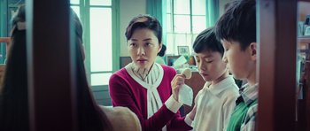 Movie still from “Ip Man 3” (2015), directed by Wilson Yip – A woman and a boy are holding a piece of food; Medium shot, Over the shoulder angle