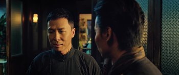 Movie still from “Ip Man 3” (2015), directed by Wilson Yip – A man standing next to another man in front of a window; Close Up shot, Over the shoulder angle