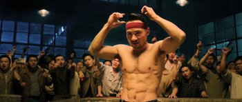 Movie still from “Ip Man 3” (2015), directed by Wilson Yip – A man with no shirt is holding his hands up to his head; Medium shot, Low angle