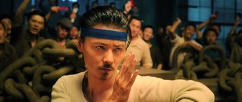Movie still from “Ip Man 3” (2015), directed by Wilson Yip – A man with a blue headband is holding his hands up; Close Up shot, Low angle