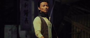 Movie still from “Ip Man 3” (2015), directed by Wilson Yip – A man wearing a vest and a neck scarf; Medium shot, Low angle