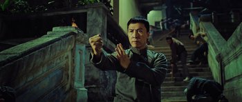 Movie still from “Ip Man 3” (2015), directed by Wilson Yip – A man in a green shirt is doing a martial arts move; Medium shot, Low angle