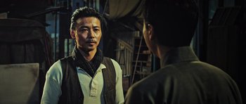 Movie still from “Ip Man 3” (2015), directed by Wilson Yip – A man standing next to another man in a room; Medium shot, Over the shoulder angle
