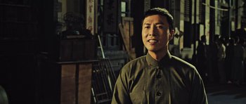 Movie still from “Ip Man 3” (2015), directed by Wilson Yip – A man standing in front of a wooden chair; Medium shot, Low angle