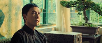 Movie still from “Ip Man 3” (2015), directed by Wilson Yip – A man sitting in front of a window with a plant; Close Up shot, Low angle
