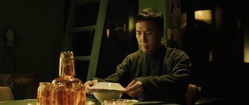 Movie still from “Ip Man 3” (2015), directed by Wilson Yip – A man sitting at a table with a bowl of food; Medium shot, Low angle