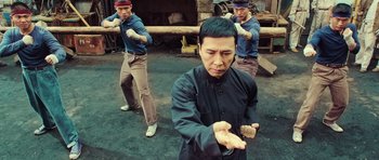 Movie still from “Ip Man 3” (2015), directed by Wilson Yip – A group of men practicing martial arts in an outdoor setting; Medium shot, High angle