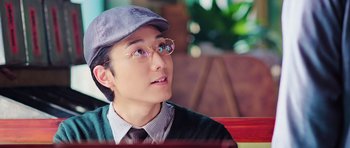 Movie still from “Ip Man 3” (2015), directed by Wilson Yip – A man wearing glasses and a hat sitting on top of a bench; Close Up shot, Low angle