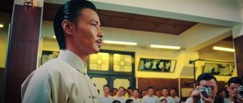 Movie still from “Ip Man 3” (2015), directed by Wilson Yip – An asian man in front of a group of people; Medium shot, Low angle