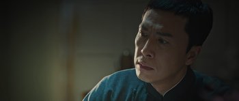 Movie still from “Ip Man 3” (2015), directed by Wilson Yip – A person sitting in front of a window; Close Up shot, Low angle