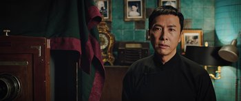 Movie still from “Ip Man 3” (2015), directed by Wilson Yip – A man standing in front of a green and red flag; Close Up shot, Low angle