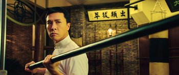 Movie still from “Ip Man 3” (2015), directed by Wilson Yip – A man in a white shirt holding a baseball bat; Close Up shot, Low angle