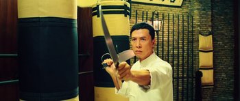 Movie still from “Ip Man 3” (2015), directed by Wilson Yip – A man holding a large pair of scissors in his hand; Medium shot, Low angle
