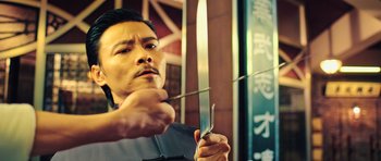 Movie still from “Ip Man 3” (2015), directed by Wilson Yip – A man holding a knife in his hand and holding a chopstick in his other hand; Close Up shot, Low angle
