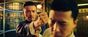 Movie still from “Ip Man 3” (2015), directed by Wilson Yip – A man is holding a knife in his right hand; Close Up shot, Over the shoulder angle