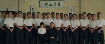 Movie still from “Ip Man 3” (2015), directed by Wilson Yip – A group of men standing next to each other in front of a painting; Medium shot, High angle