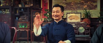 Movie still from “Ip Man 4: The Finale” (2019), directed by Wilson Yip – A man in a blue and white shirt holding his hand up; Medium shot, Over the shoulder angle