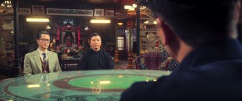 Movie still from “Ip Man 4: The Finale” (2019), directed by Wilson Yip – A man sitting at a table in front of another man; Medium shot, Over the shoulder angle