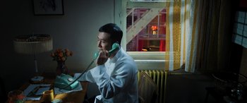 Movie still from “Ip Man 4: The Finale” (2019), directed by Wilson Yip – A man sitting at a table talking on a phone; Medium shot, High angle