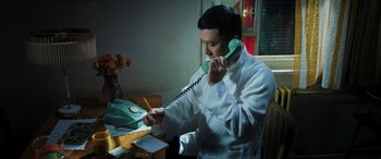 Movie still from “Ip Man 4: The Finale” (2019), directed by Wilson Yip – A man sitting at a table talking on a phone; Medium shot, High angle
