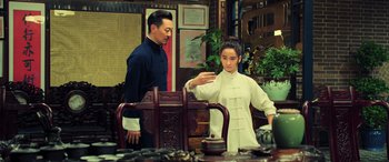 Movie still from “Ip Man 4: The Finale” (2019), directed by Wilson Yip – A man and a woman standing next to each other in a room; Medium shot, Over the shoulder angle